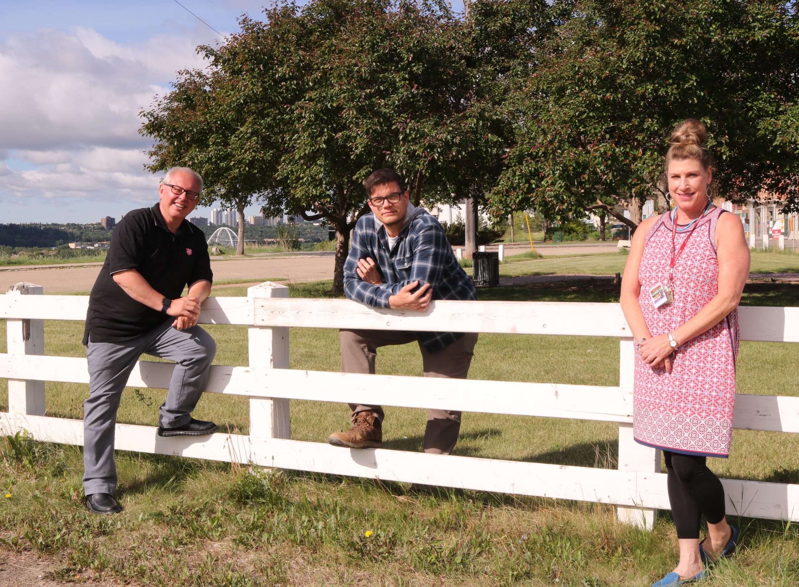 three people leaning on fence