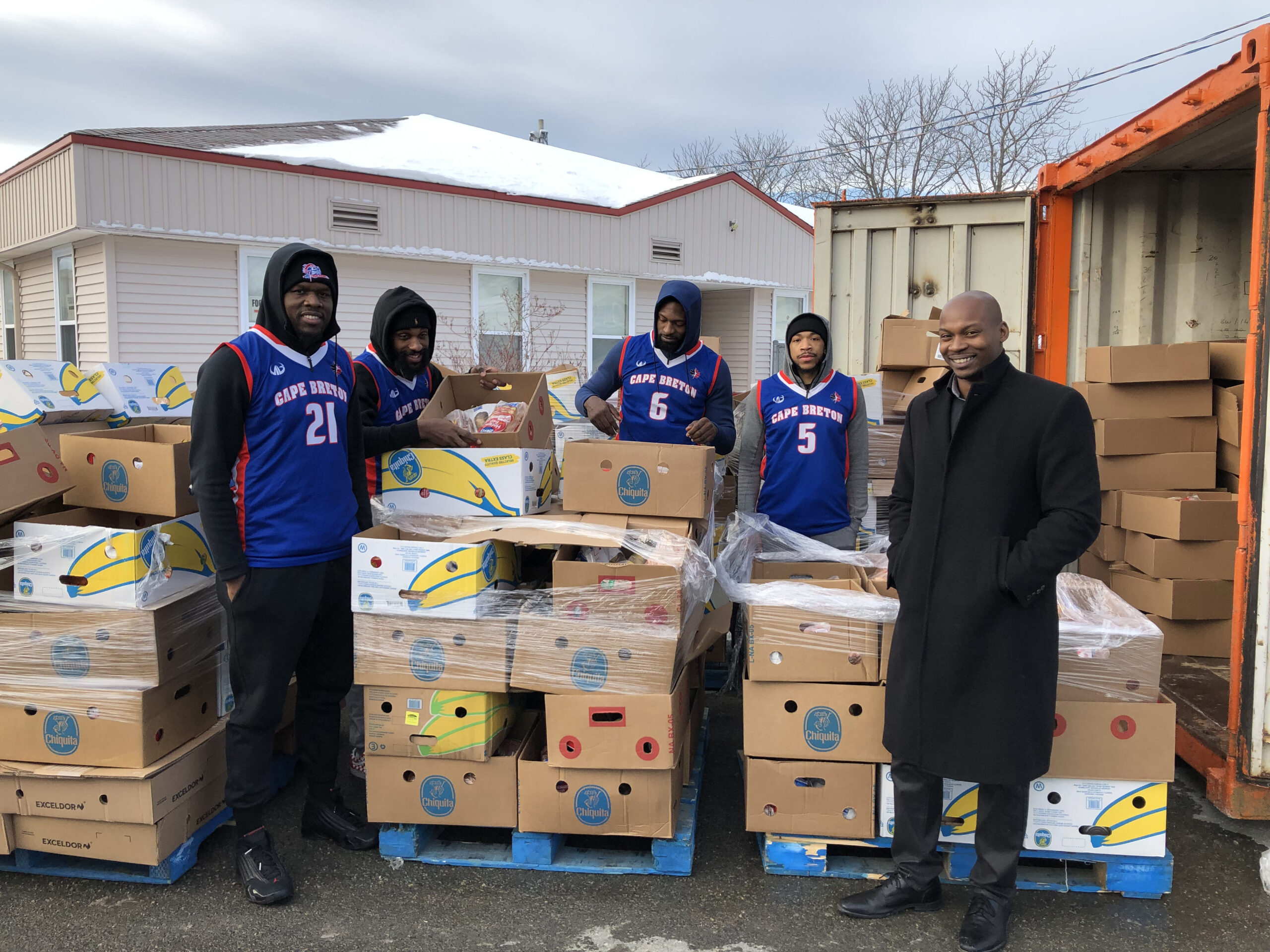 Basketball team stands around boxes of food