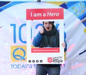 Participant photographed under "I am a Hero" sign