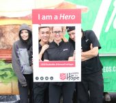 Participants are photographed under sign "I am a Hero"