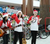 Three girls sing and play tambourine and guitar at toy mountain kickoff