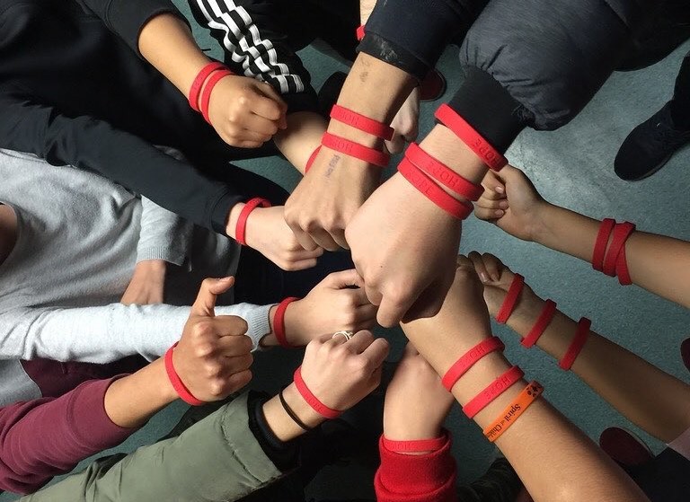 Several hands together as fists earing bracelets