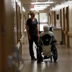a worker and a patient talking in a hall. the patient is in a wheelchair