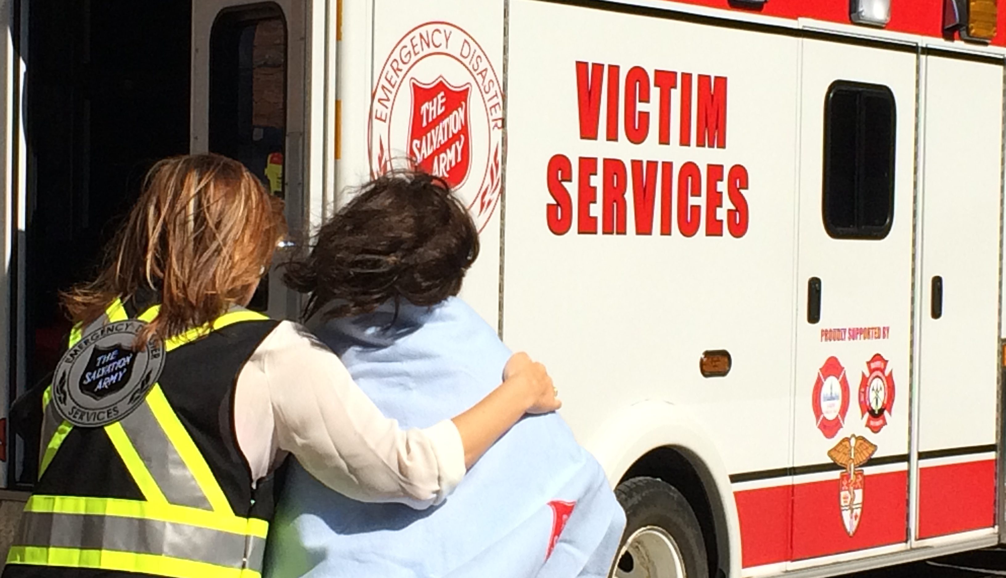 An EDS personnel helping a lady to a Salvation Army victim services vehicle