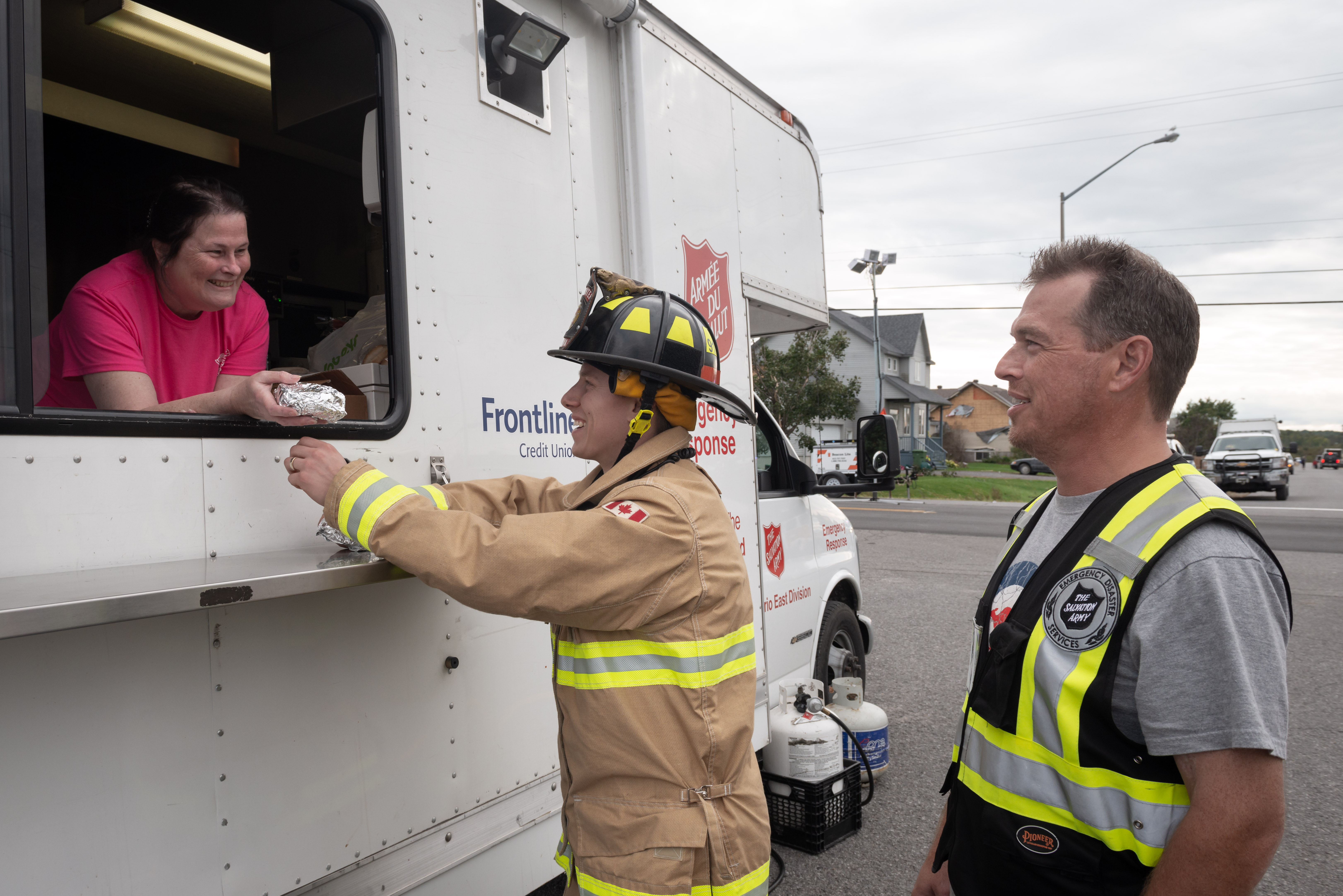 Salvation Army volunteer hands a refreshment to a firefighter from the mobile canteen truck