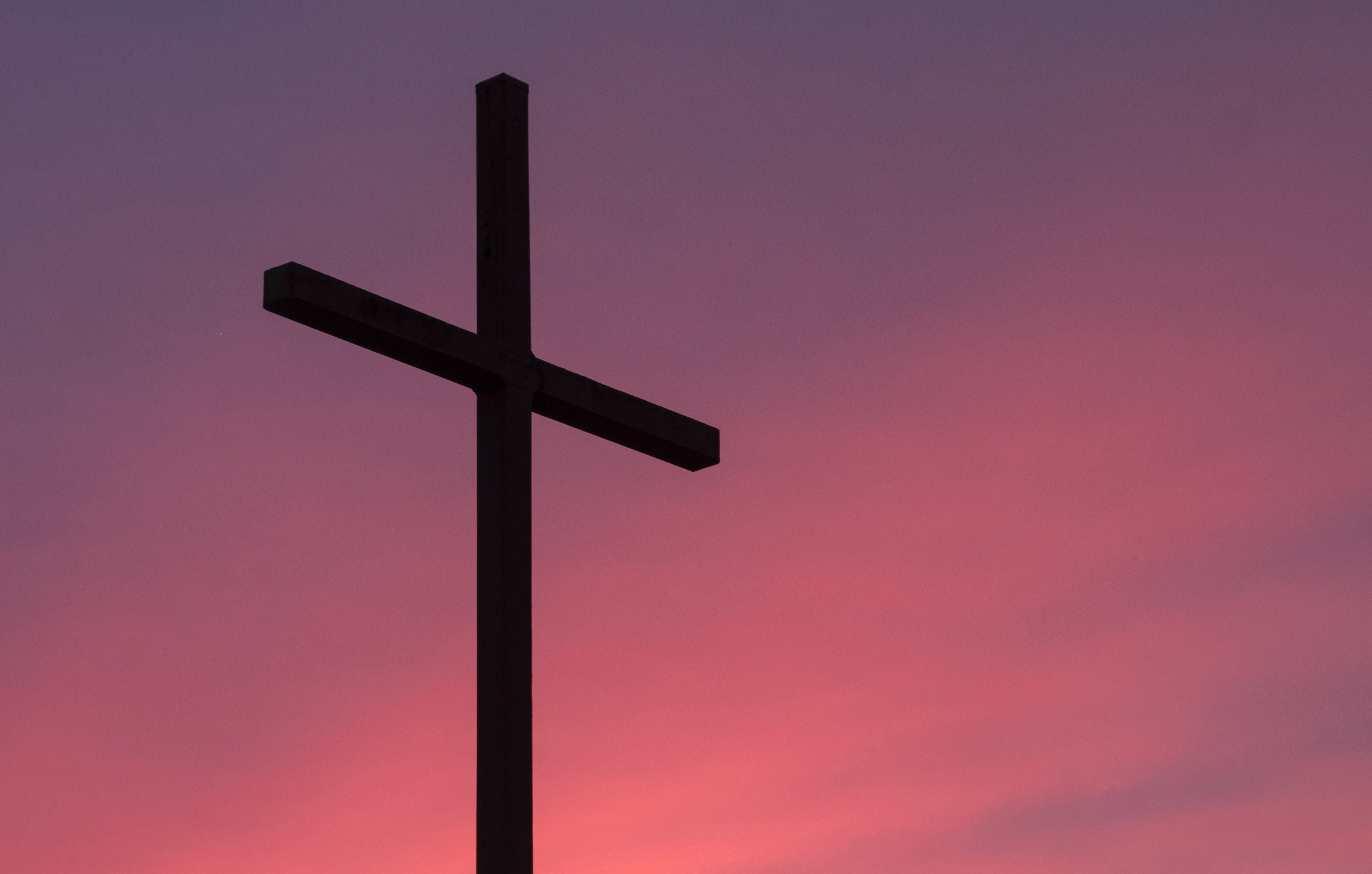 Photo of a cross with a sunset in the background