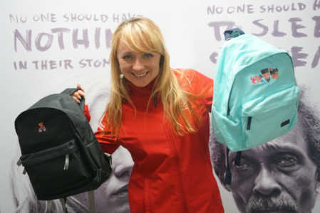 Photo of Salvation Army employee holding up two backpacks