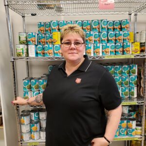 Sandra stands infront of canned goods in a food bank