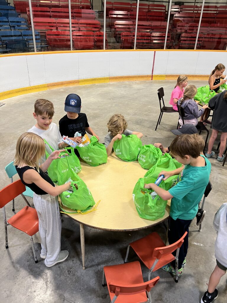 Children around a table looking into snack bags