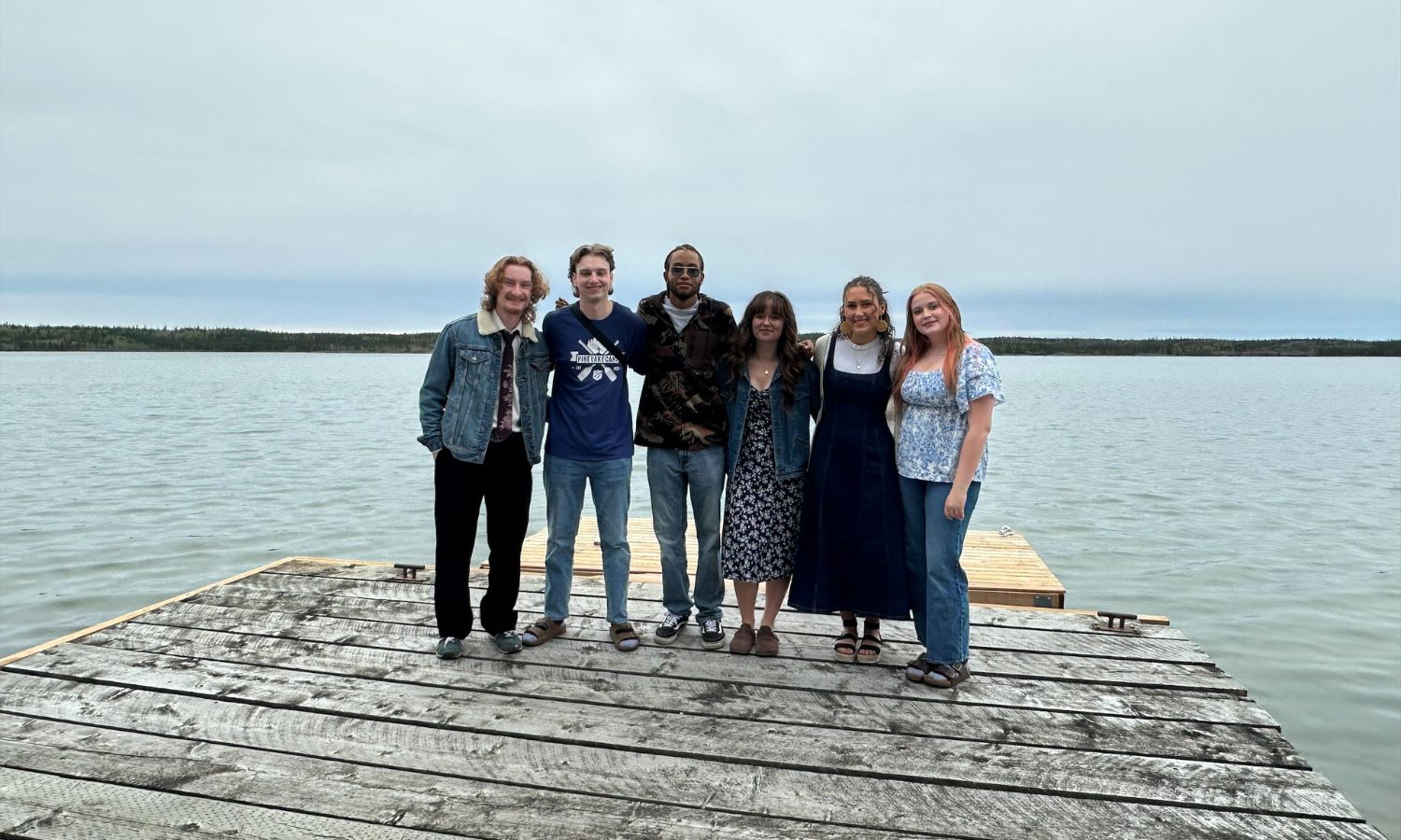 Six youths standing on a dock, smiling.