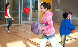 Children playing with basketballs inside of a gymnasium