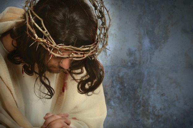 Jesus with crown of thorns with head down over old wall