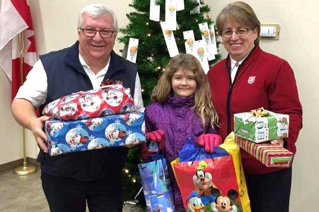 Man and child and Salvation Army worker stand in from of Salvation Army medicine hat angel tree