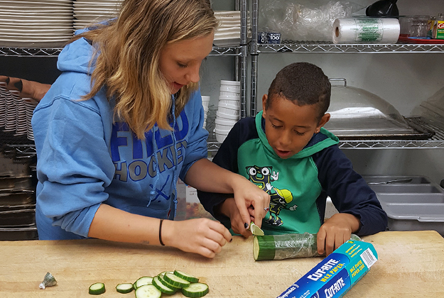 Jamie-Lynn (left) cuts cucumber with after-school participant