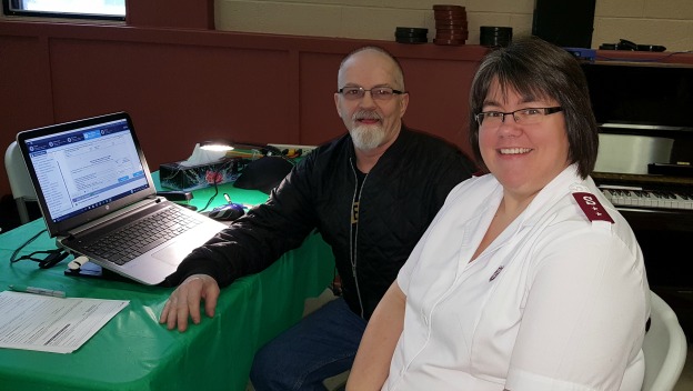 volunteer, Jerry (left) sits with laptop to prepare income tax with church pastor Danette Woods (right)