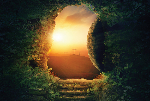 Inside a tomb looking out to three crosses on a hill at sunset