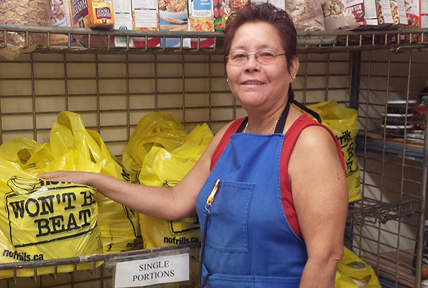 Philomena distributes food in yellow plastic bags at food bank