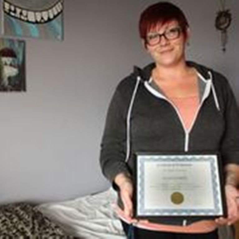 A woman named Randi holding her certificate of graduation