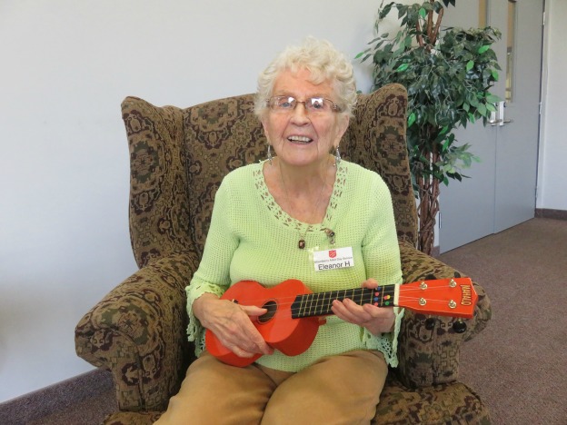 Eleanor sits on chair learning Ukulele at adult day program