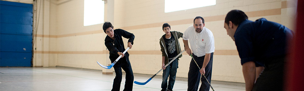 Social Services- a Salvation Army employee playing floor hickey with 3 other men