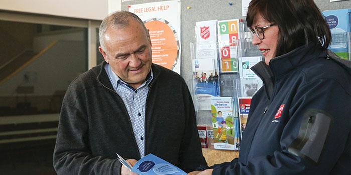 A salvation Army employee showing a pamphlet to a man