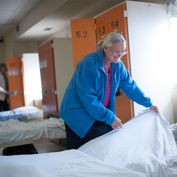 Housing And Shelters- a woman making a bed in a shelter