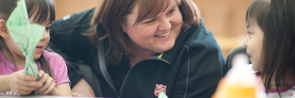 Salvation Army worker smiling at children who are smiling back