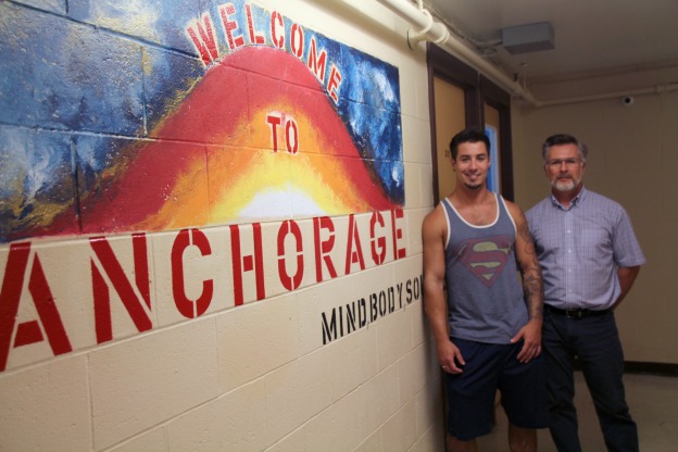 Cory stands alongside Paul, his counsellor by the Anchorage addictions program sign