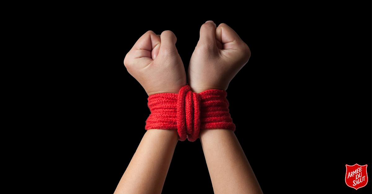a pair of hands tied by a red knot depicts the trafficked person