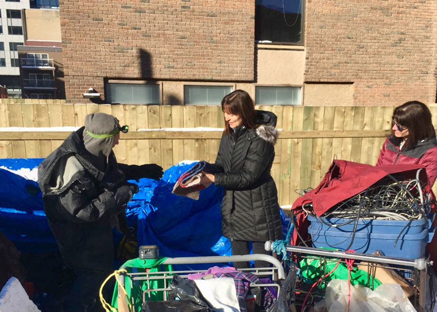 Volunteers deliver hand-knit scarves to homeless man living under tarp