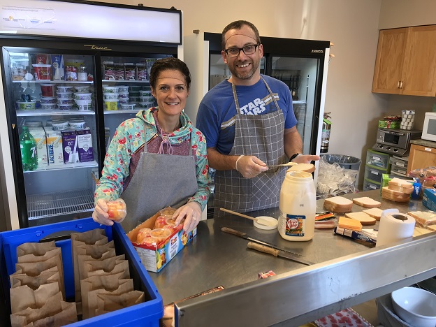 Two volunteers prepare lunches for hungry students