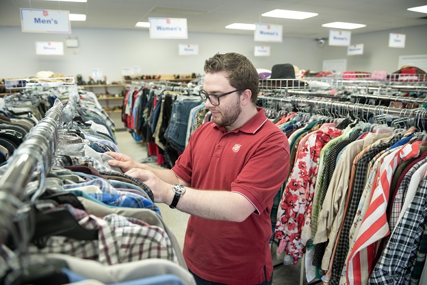 Thrift store employee sorts through racks of clothes in the store