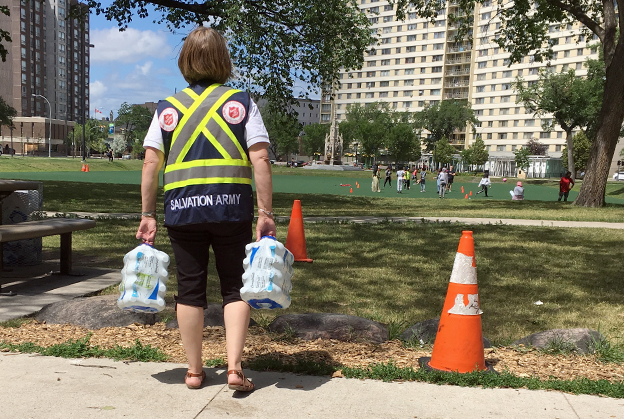 salvation army worker distributes cold water to vulnerable people during heat wave