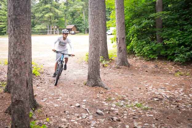 camper on bike riding through trees
