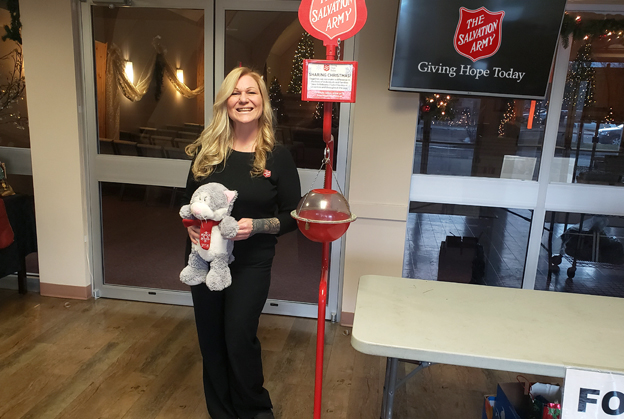 Angela stands by kettle holding donated stuffed bear