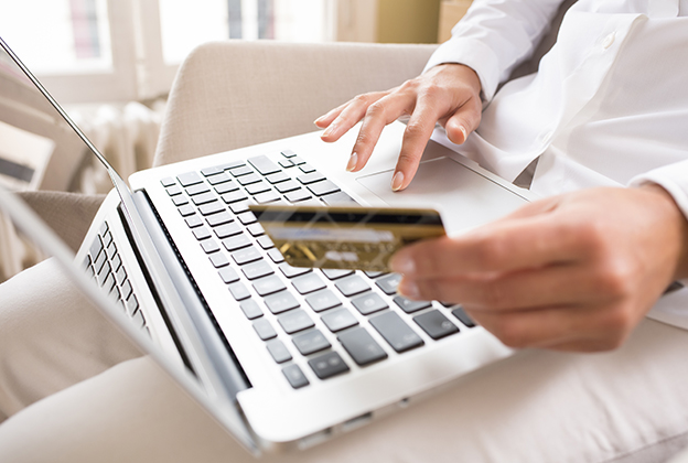 Woman holding a credit card and using computer, online