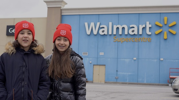 two children with Salvation Army hats stand by Walmart store