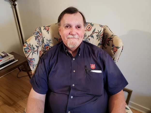 Chris sits in his living room with Salvation Army branded shirt