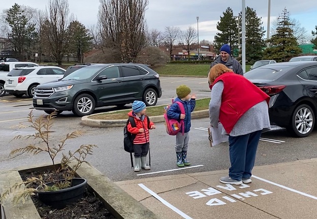 Child care worker uses social distancing to greet children