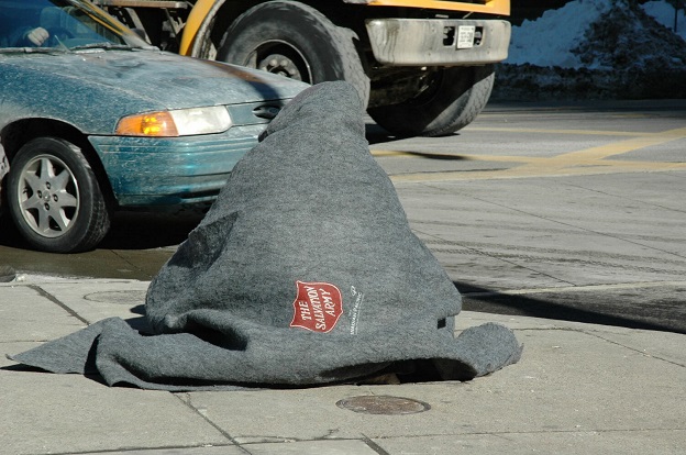 Homeless person sits with SA blanket wrapped around