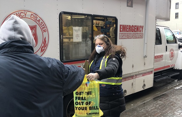 Salvation Army worker hands bag of food to client from disaster services truck
