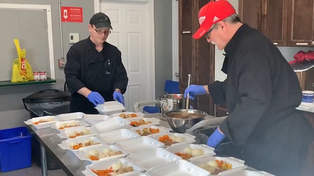 Salvation Army workers prepare meals in clam shells for distribution to the vulnerable