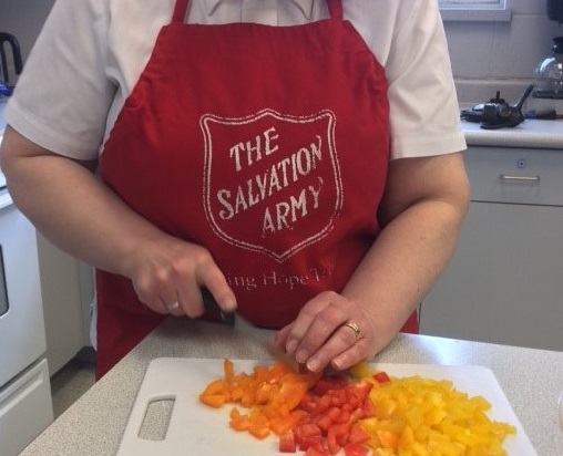 Salvation Army pastor in volunteer apron cuts fresh food for delivery