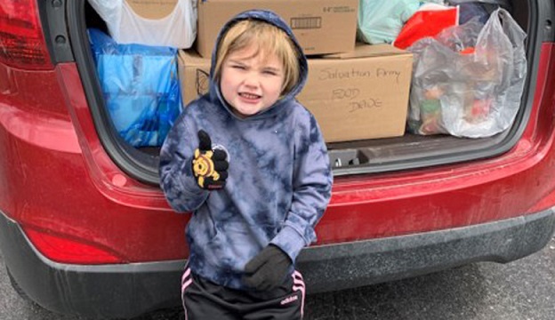 five-year-old Kennedy stands in front of trunk full of food from her food drive