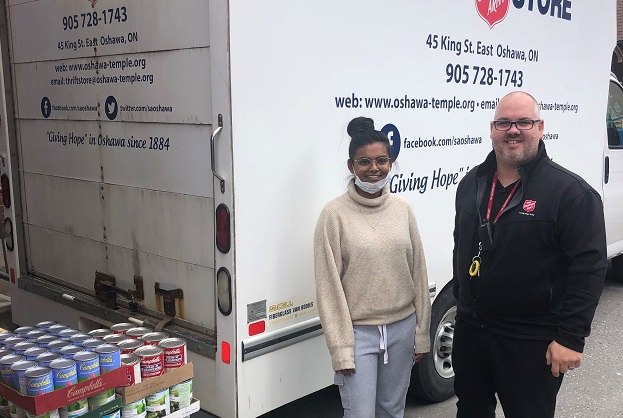cans of food sit by Salvation Army truck. Donor and Community and family services director stand alongside