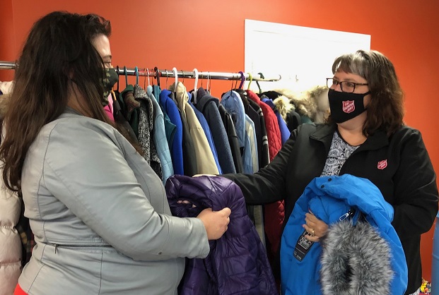 Salvation Army worker hands a winter coat to client