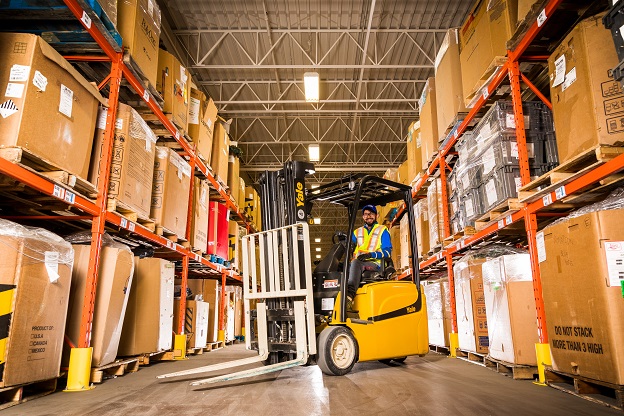 Fork lift driver in warehouse full of boxes