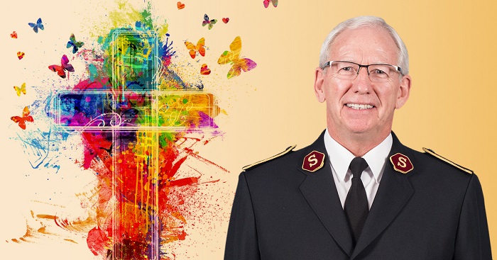 General Brian Peddle stands beside a multi-coloured cross
