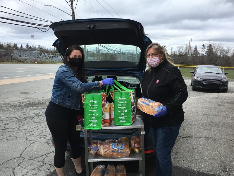 Two volunteer pack their van with food items to deliver to people in isolation