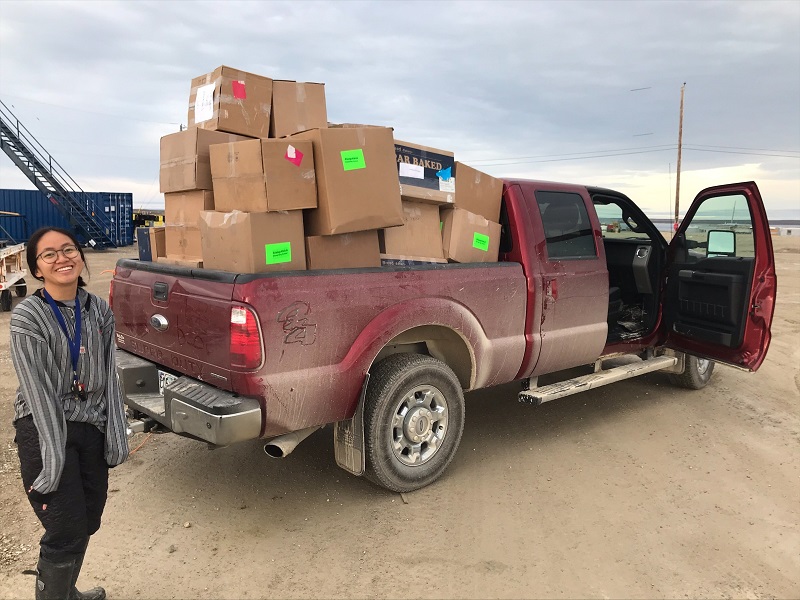 Igloolik teacher, Colleen, stands beside pick up truck with boxes of winter wear